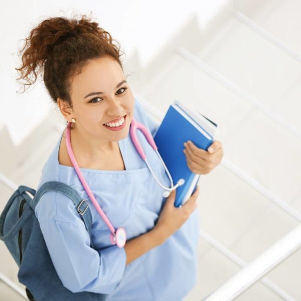 happy nursing student with stethoscope walking up the stairs holding her books, studying associate degree in nursing online