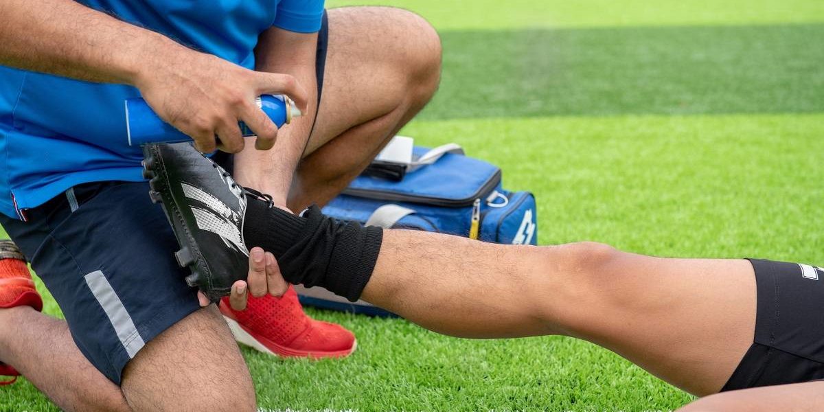 college athlete, football player injured lying on the field getting help from a friend