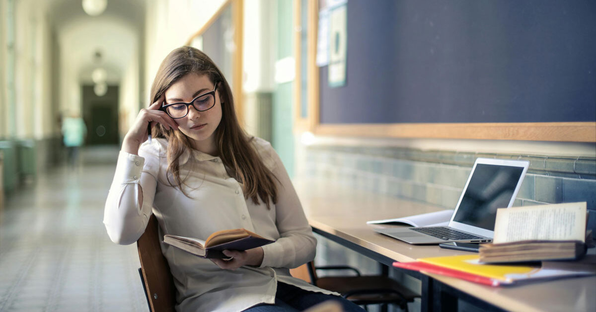 a woman sitting at a desk reading a book