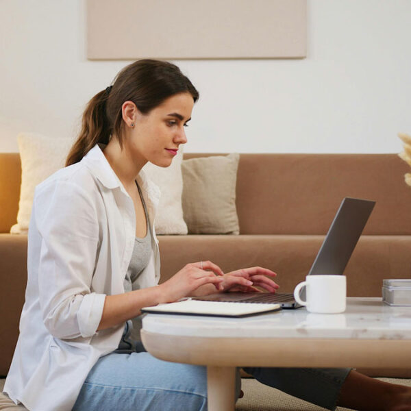a woman sitting on a coffee table using a laptop