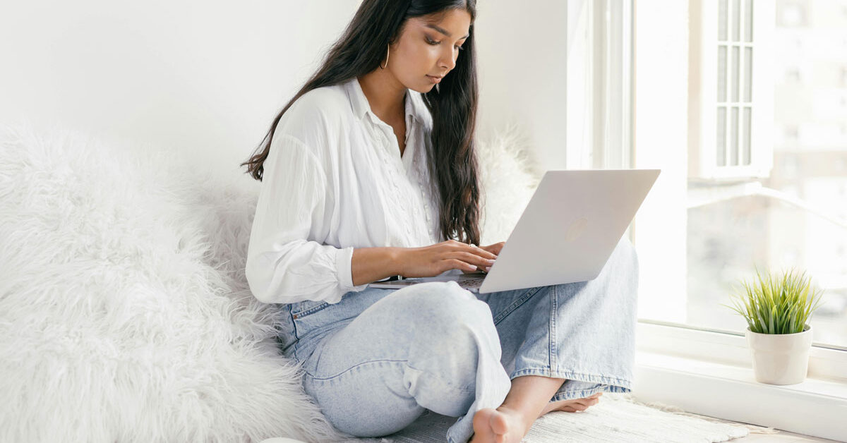 a woman sitting on a rug with a laptop