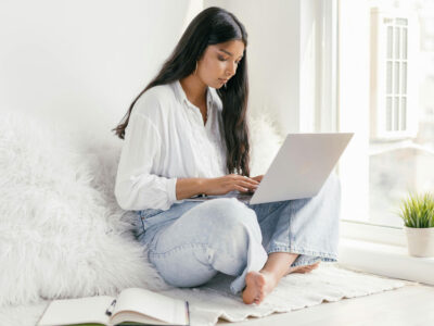 a woman sitting on a rug with a laptop