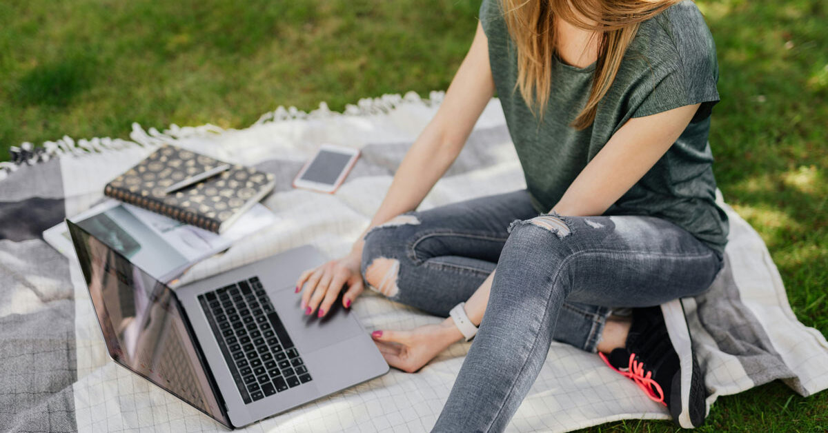 a woman sitting on a blanket with a laptop