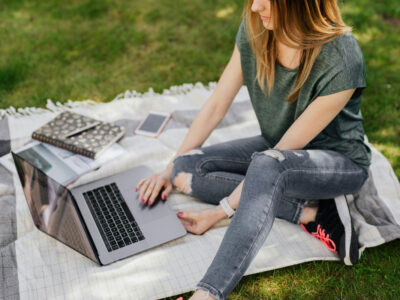 a woman sitting on a blanket with a laptop