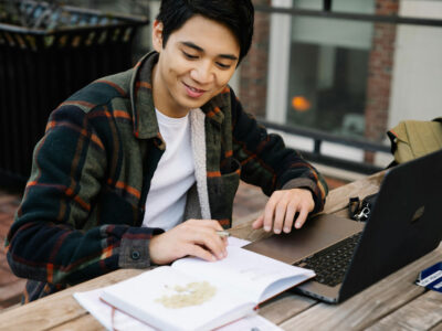 a man sitting at a table with a laptop and a book
