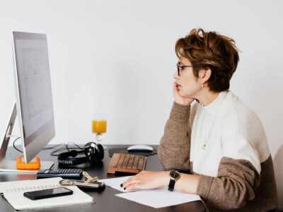 a woman sitting at a desk looking at a computer screen