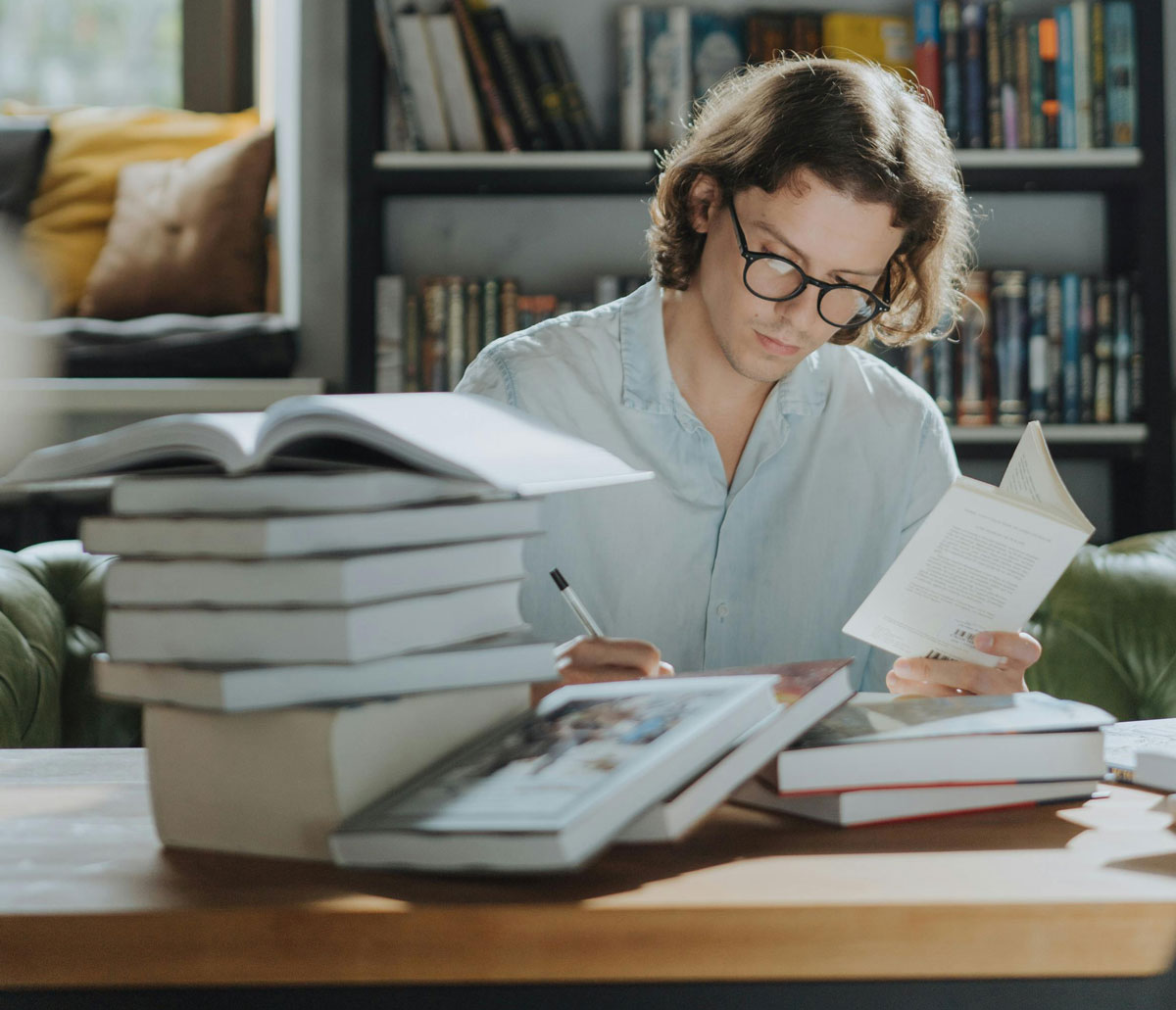 a man sitting at a table with books and a bookcase