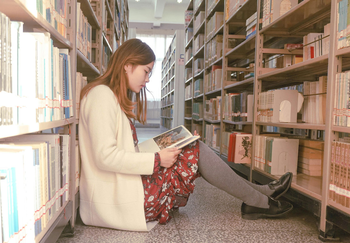a woman sitting on the floor reading a book
