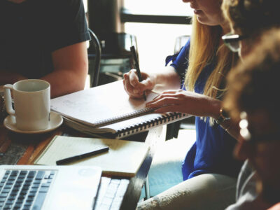 a group of people sitting at a table writing on a notebook