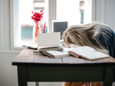 a woman with her head on a desk with books