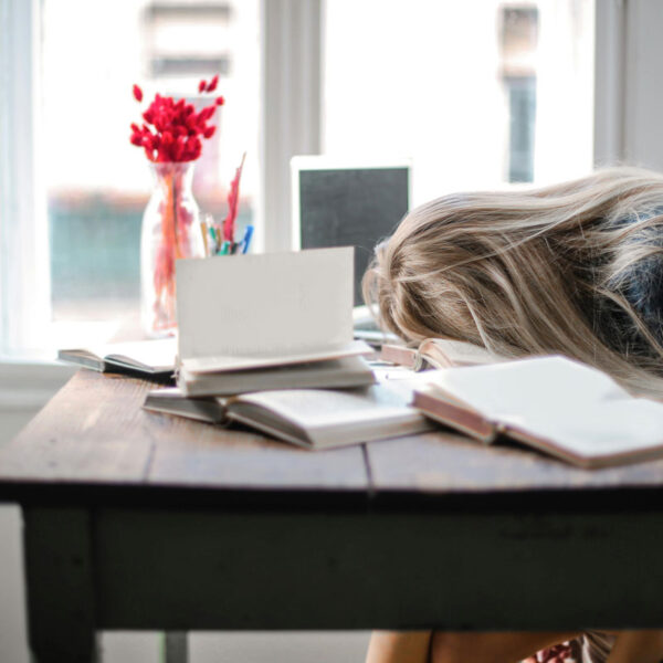 a woman with her head on a desk with books