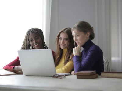 a group of women looking at a laptop